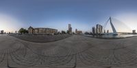 a fish eye lens image of the city in view from a brick area with a pedestrian bridge in the foreground