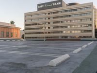 a parking lot full of a city bank building next to a street sign and a parking meter