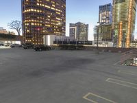 several tall buildings sit in an empty parking lot, with two parked trucks next to each other