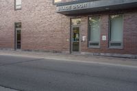 the entrance to the brick building is empty on the street, as a person walks down a sidewalk