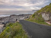 a paved paved path runs down from the sea and the shore to a rocky coast