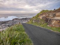 a paved paved path runs down from the sea and the shore to a rocky coast