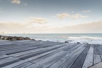 a dock with a person on the beach in the distance and the ocean water in the background