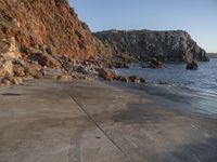 a stone walkway leading to a rocky coastline near the water's edge with a beach in the foreground