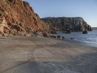 a stone walkway leading to a rocky coastline near the water's edge with a beach in the foreground