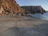 a stone walkway leading to a rocky coastline near the water's edge with a beach in the foreground