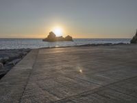 a skateboarder is doing tricks next to a rocky shore at dusk on a sunny day