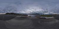 a fish eye lens is shown on a camera roll with clouds above the water and a small boat on a dock in front