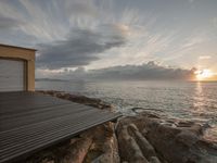 a pier in the middle of the ocean with rocks on it and a sky view with clouds