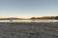 a field is in front of some water with a bench in the center and mountains