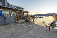 two motorcycles sit parked in front of a store near the water with many boats in the background