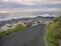 a road on the side of a rocky cliff on the beach next to the water