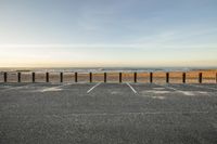 a parking lot with a sign posted on it beside the ocean in the sunset at the beach