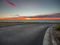 a beautiful view of a sunset with the ocean in the distance from a parking lot