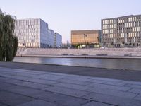 three large building in a city on one side of a canal and several buildings on the other