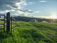 a lone country road is in the countryside area with mountains on both sides and barbed fence between the two sides