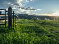 a lone country road is in the countryside area with mountains on both sides and barbed fence between the two sides