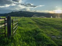 a lone country road is in the countryside area with mountains on both sides and barbed fence between the two sides