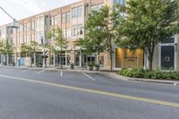 an empty street in front of a large building with windows on each side of the street