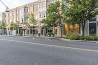 an empty street in front of a large building with windows on each side of the street