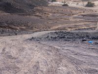 a truck on a dirt road in the desert with rocks and stones on the ground