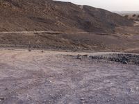 a truck on a dirt road in the desert with rocks and stones on the ground