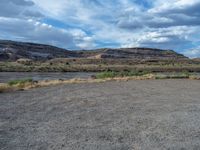 a dirt field that has some trees on it and a small mountain in the distance