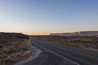 an empty highway at sunset on the edge of some rocky desert lands in utah, usa
