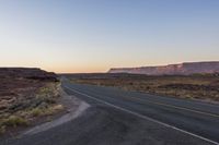 an empty highway at sunset on the edge of some rocky desert lands in utah, usa