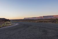 an empty highway at sunset on the edge of some rocky desert lands in utah, usa