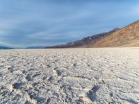 a desert like land with a sandy shore and mountains in the distance in the background