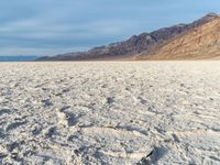 a desert like land with a sandy shore and mountains in the distance in the background