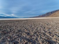 this barren desert is covered with rocks and gravel and a cloudy blue sky is seen