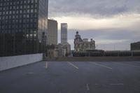 a parking lot with buildings in the background and some clouds in the sky above them