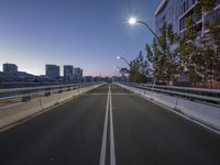 an empty freeway with a bright light shining in the distance behind it and traffic lights on the left side