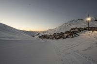 a mountain is dotted with tracks as people ski and snowboard at sunset outside of town