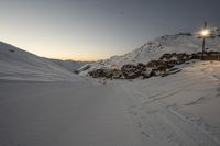 a mountain is dotted with tracks as people ski and snowboard at sunset outside of town