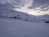 a person skiing on the snow in front of some ski lift with snow and clouds behind them