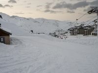 a person is skiing near a snow covered mountain side area and a ski lift is in the background