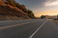 a truck driving on the highway during sunset on an empty road near the mountains,