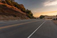 a truck driving on the highway during sunset on an empty road near the mountains,