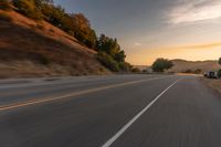 a truck driving on the highway during sunset on an empty road near the mountains,