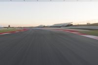 the view from the back of a racing car's car as it speeds along a track at sunset