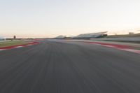 the view from the back of a racing car's car as it speeds along a track at sunset