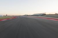 the view from the back of a racing car's car as it speeds along a track at sunset