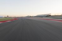 the view from the back of a racing car's car as it speeds along a track at sunset