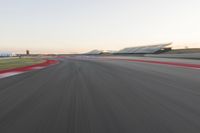 the view from the back of a racing car's car as it speeds along a track at sunset