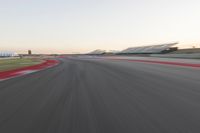 the view from the back of a racing car's car as it speeds along a track at sunset