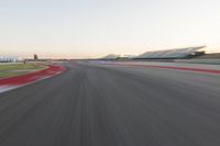 the view from the back of a racing car's car as it speeds along a track at sunset