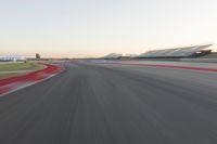 the view from the back of a racing car's car as it speeds along a track at sunset